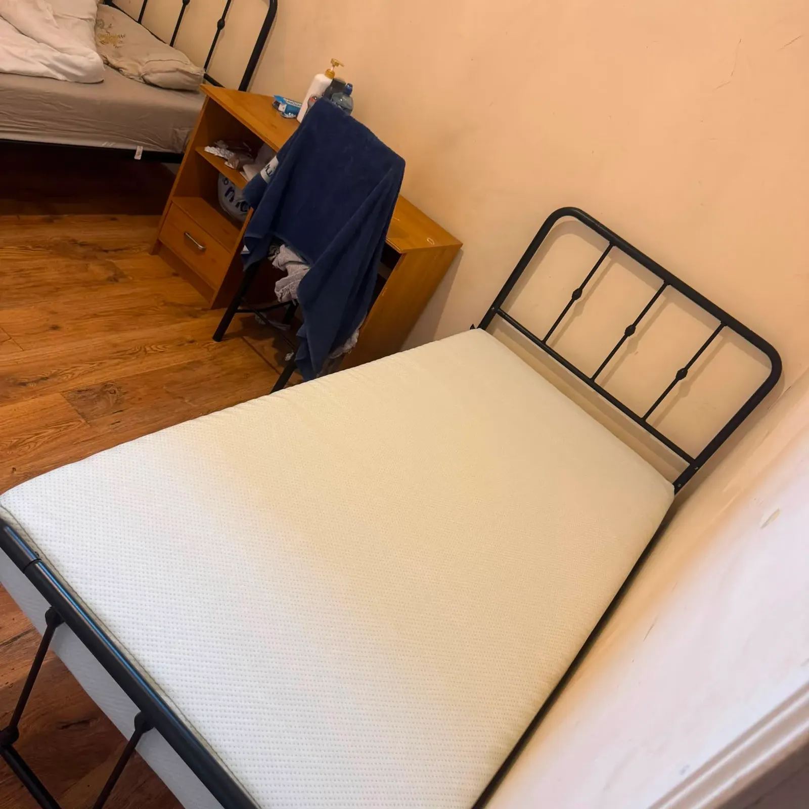 Bedroom with two single beds with metal frames, a small wooden desk and chair between them, and hardwood floor.