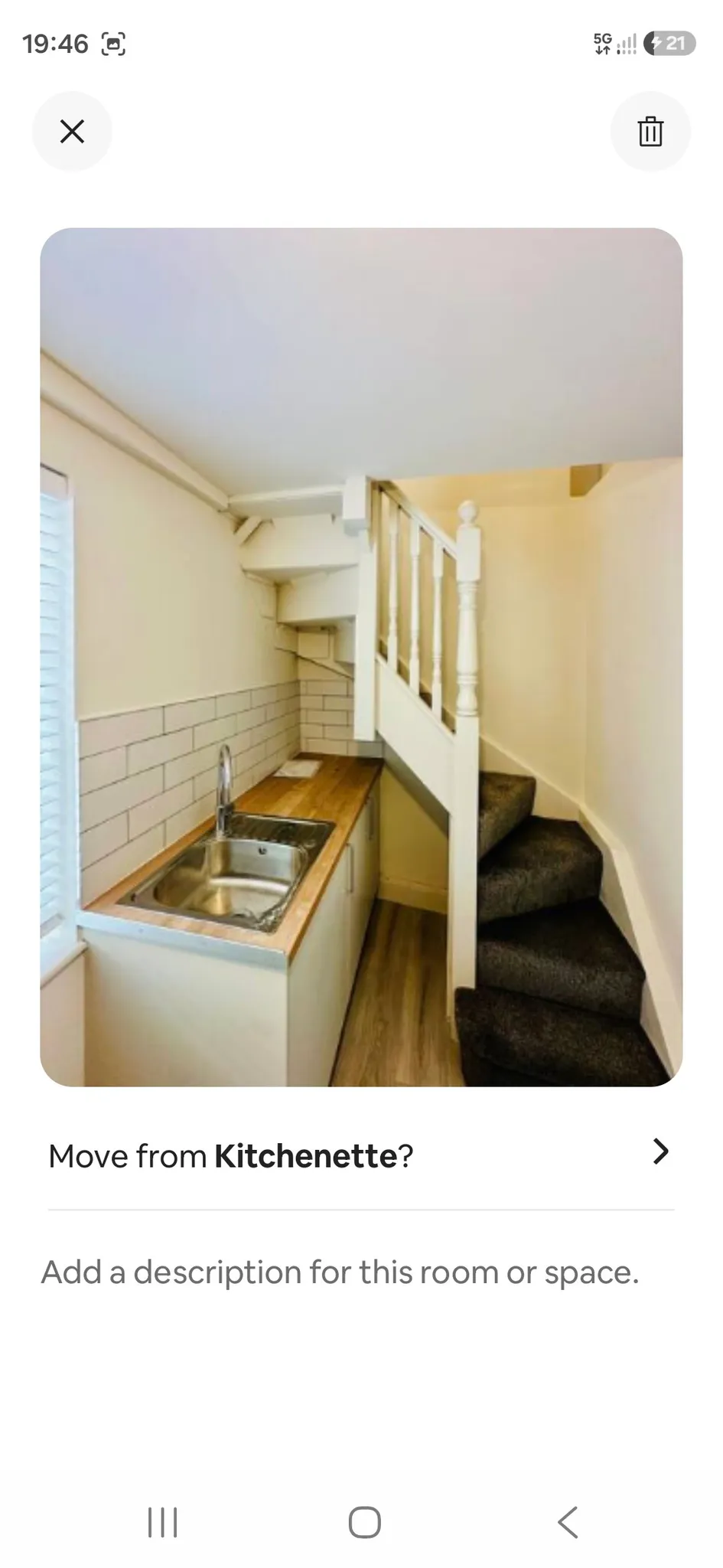 Small kitchenette with stainless steel sink, wooden countertop, white subway-tile backsplash and a carpeted staircase rising beside the counter