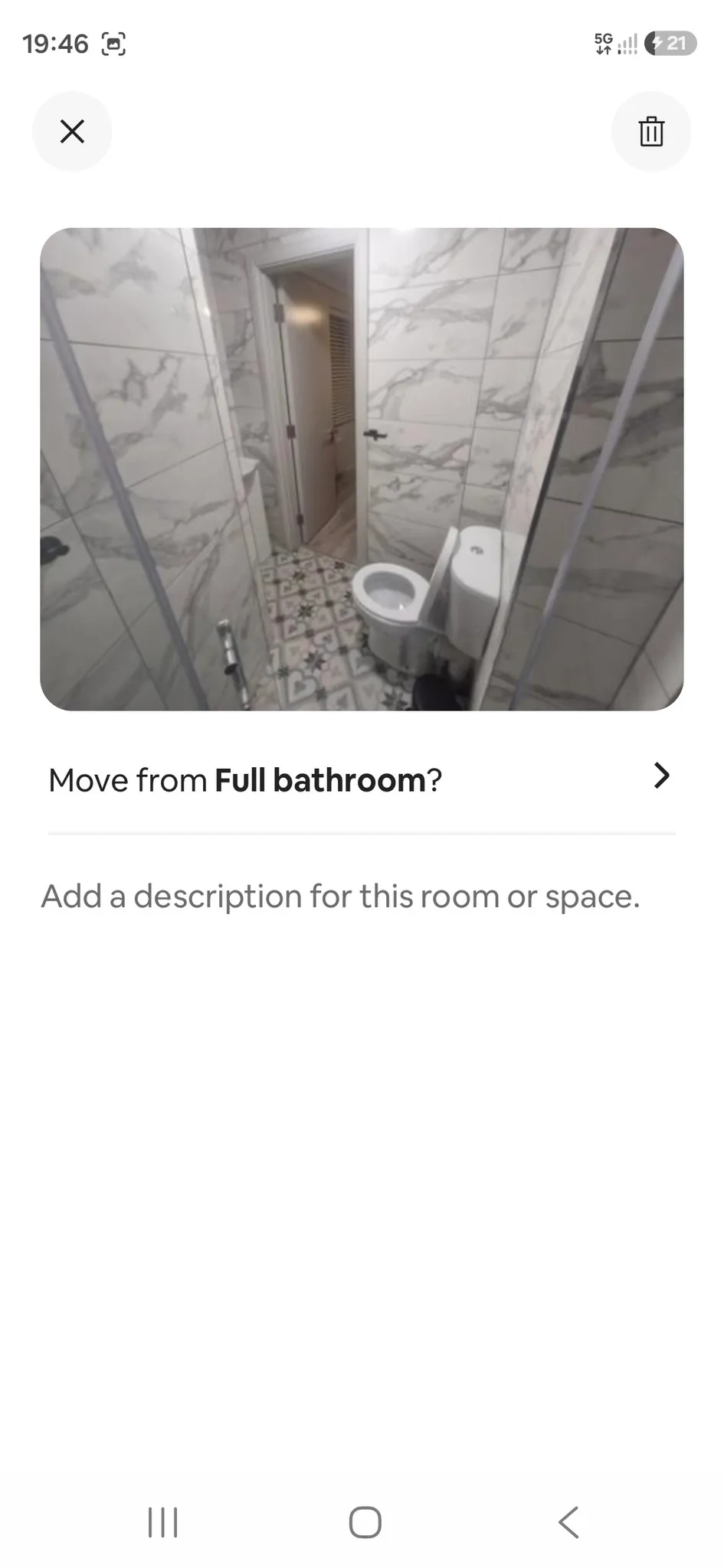 Bathroom with a toilet, tiled walls, patterned tile floor and a doorway to another room