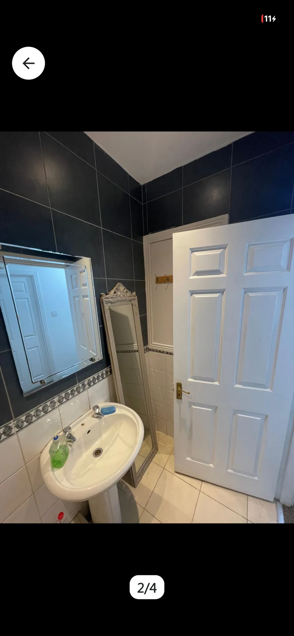 Bathroom with a pedestal sink, wall-mounted mirror, freestanding full-length mirror, tiled walls and an open white door.
