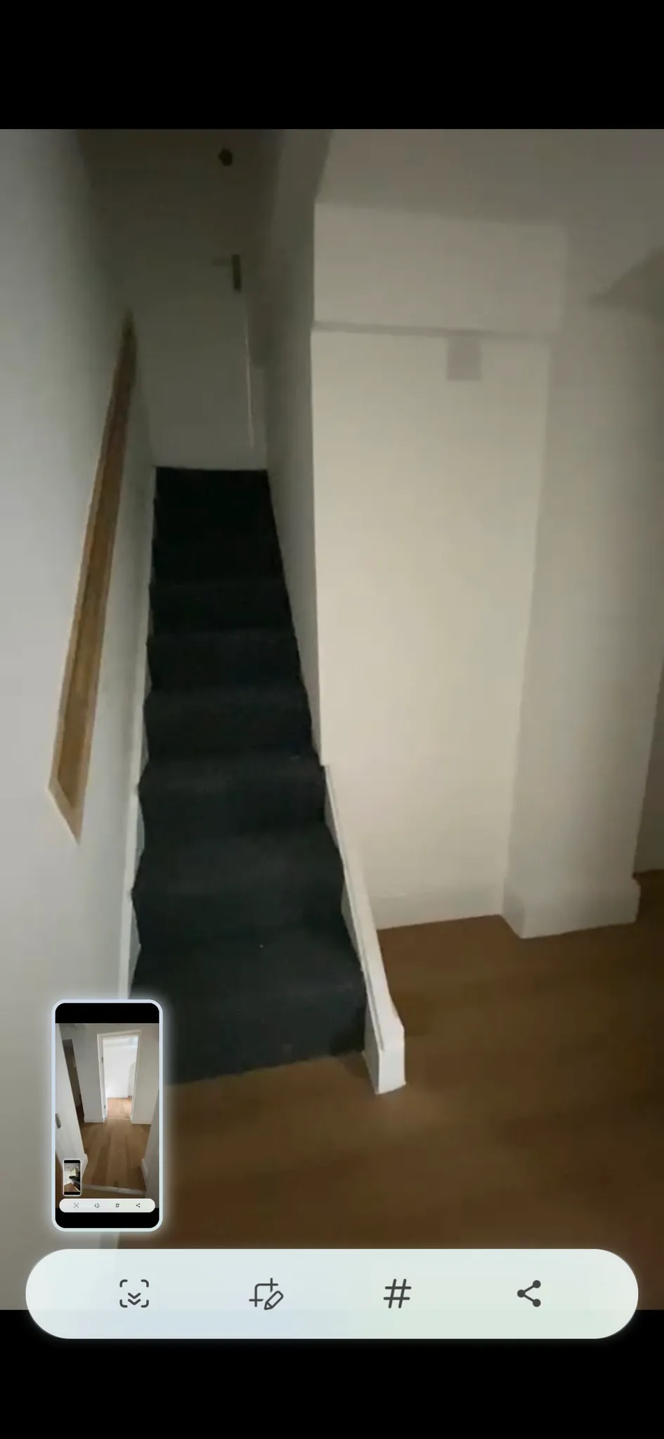 Narrow stairway with dark carpet, white walls and a wooden handrail leading upward.