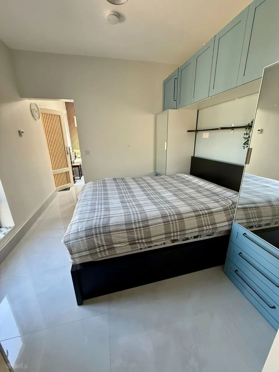 Bedroom with a double bed, built-in overhead cabinets, wardrobe with mirrored door, and tiled floor