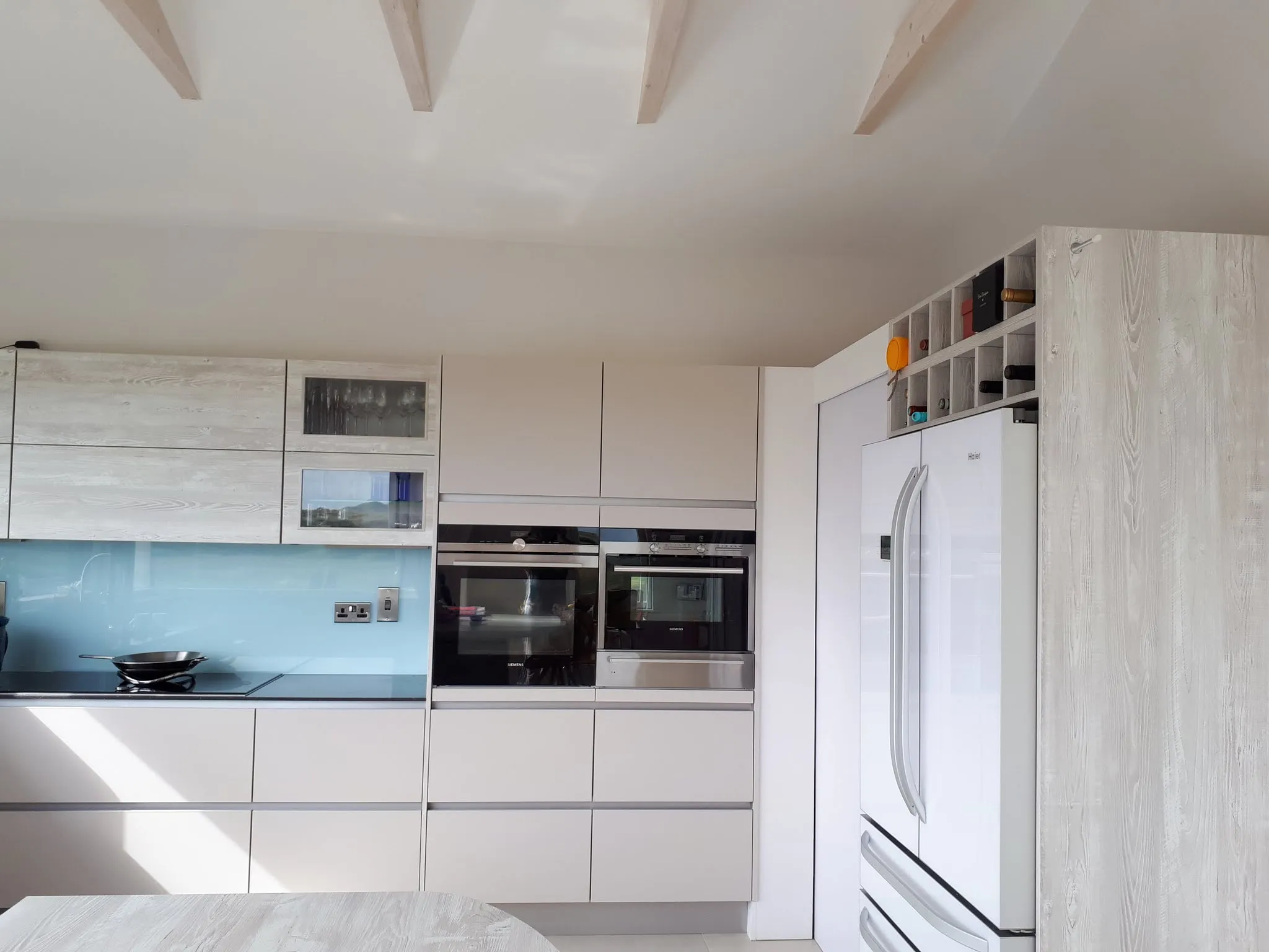 Kitchen with built-in cabinets, double wall ovens, refrigerator, glass backsplash and induction cooktop