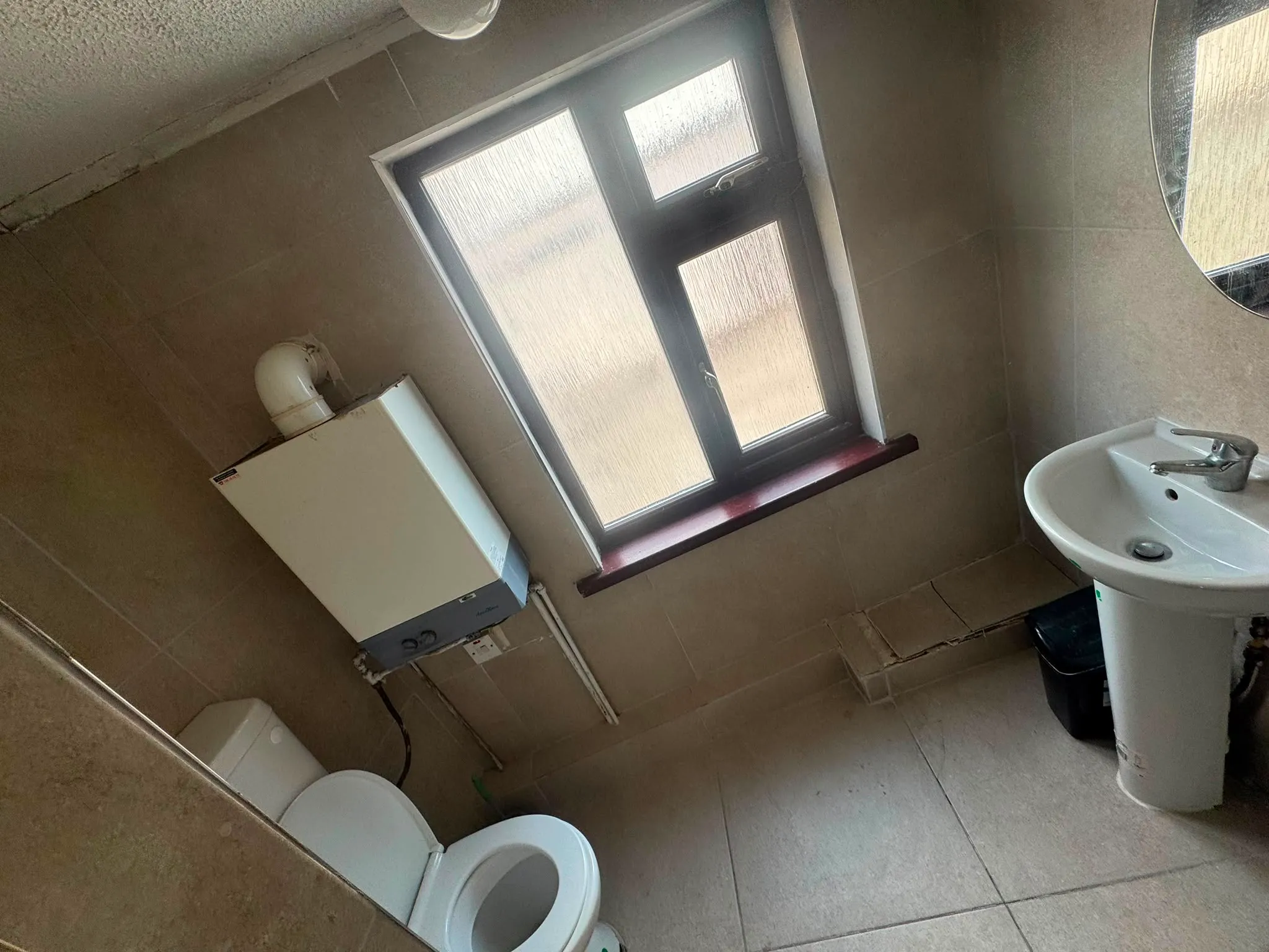 Bathroom with a frosted window, wall-mounted boiler, toilet and pedestal sink