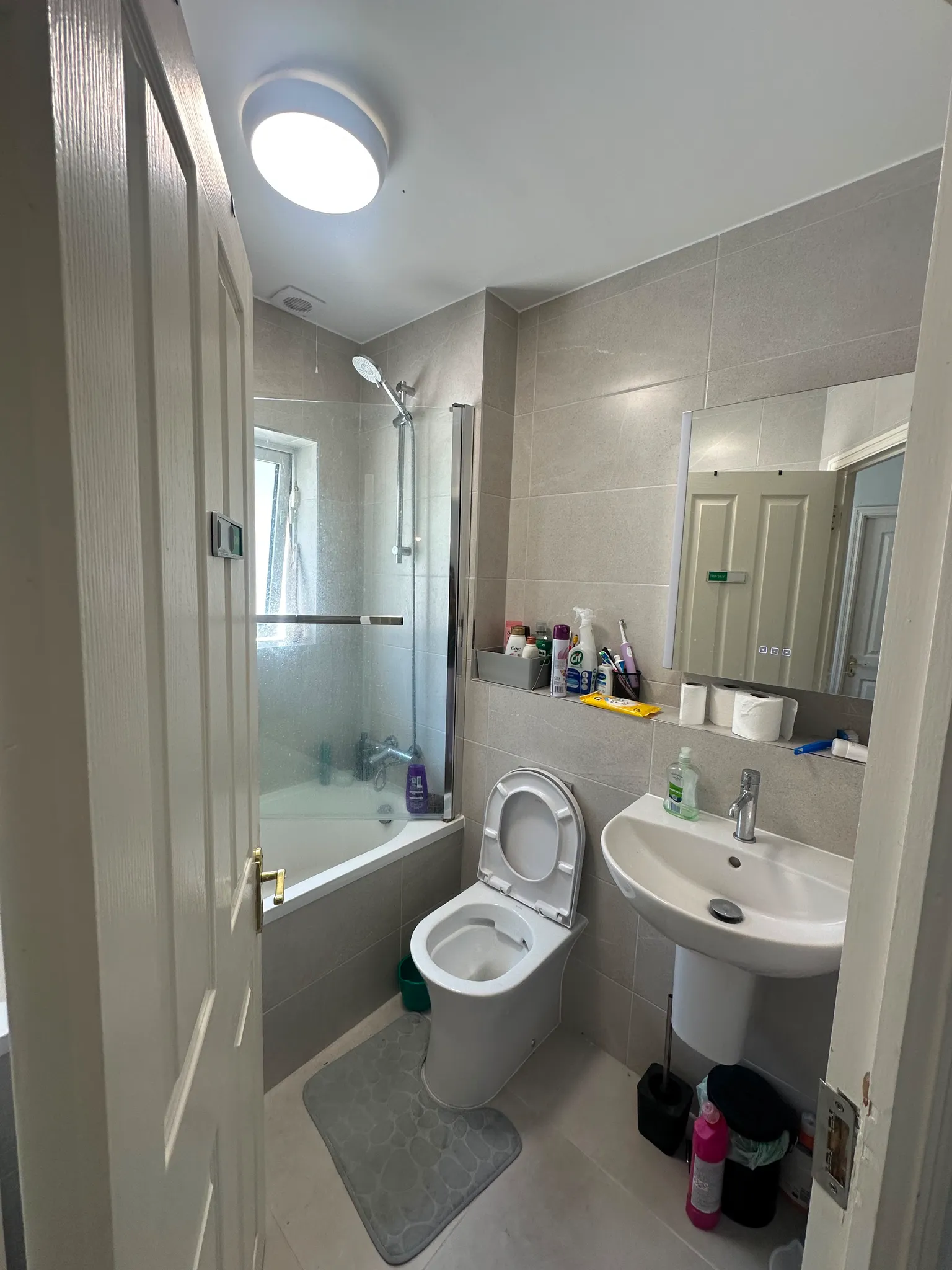 Bathroom with a toilet, pedestal sink, mirrored cabinet, and a shower with glass screen.