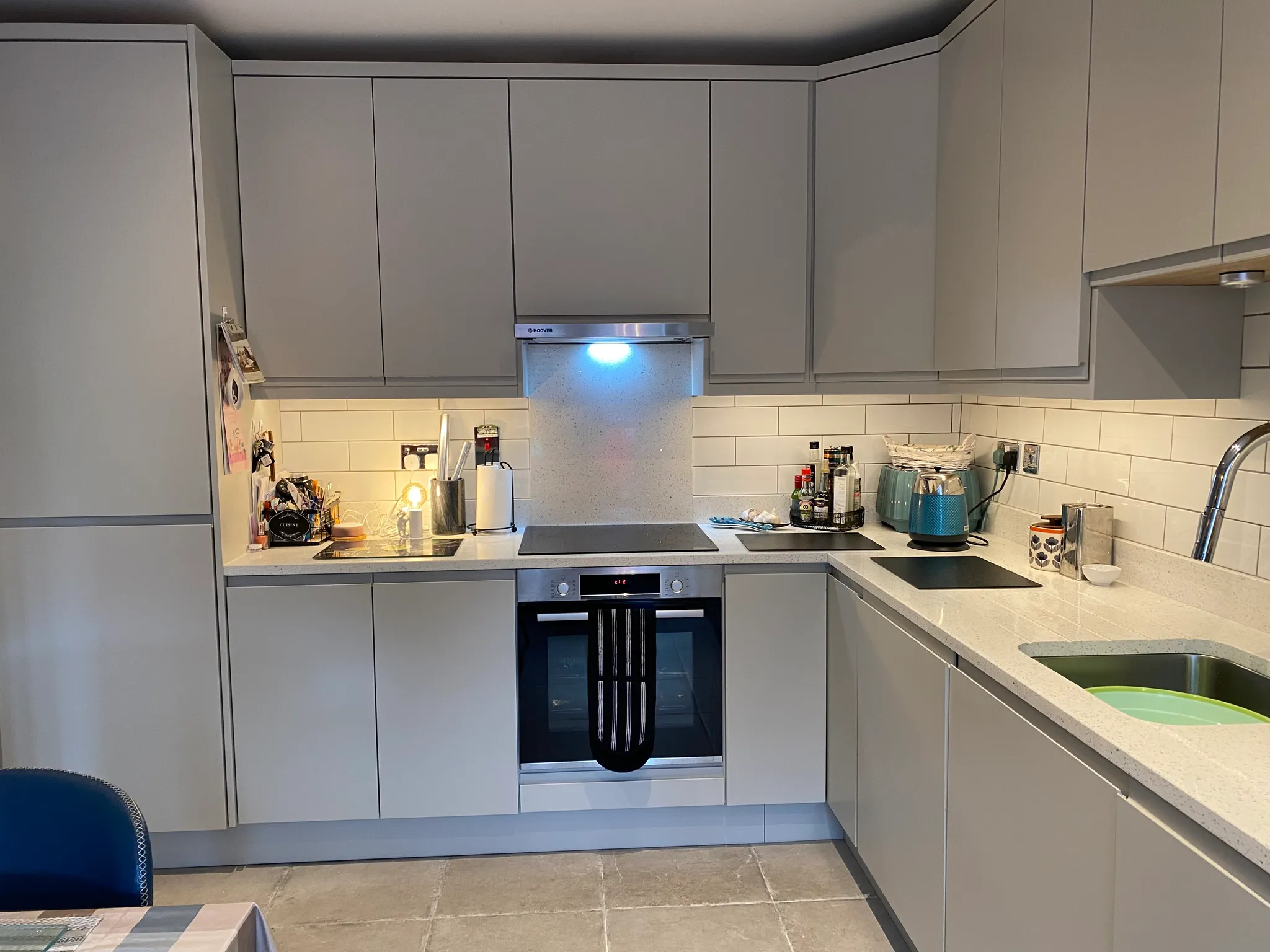 Kitchen with grey cabinets, countertop, stovetop, oven and sink