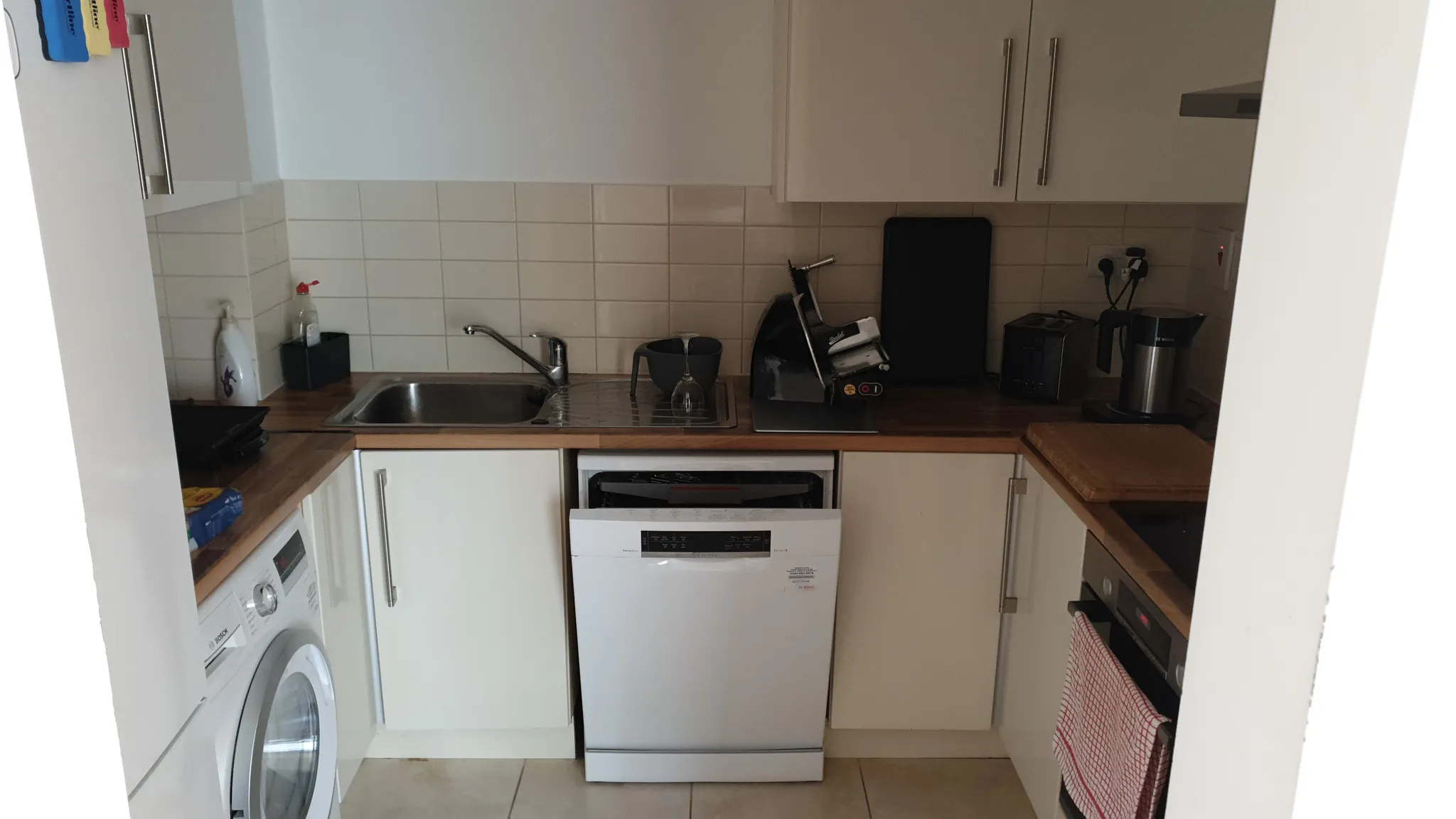 Small kitchen with a single-basin sink, countertop appliances, white cabinets and a dishwasher under the counter