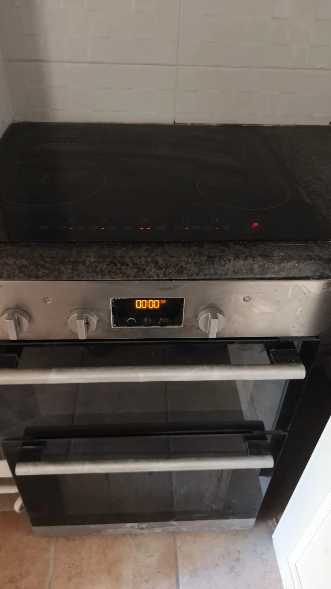 Kitchen with a built-in oven and black glass electric cooktop set into a dark countertop