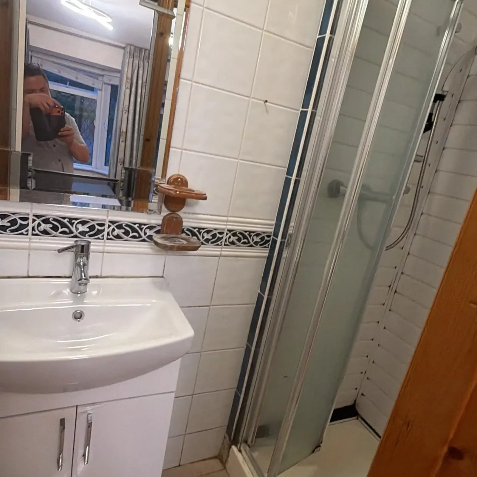 Bathroom with a sink and vanity, wall mirror, tiled walls and a corner shower with sliding glass doors